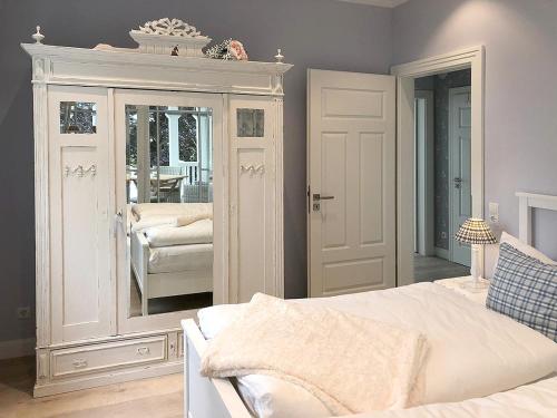 a bedroom with a white bed and a mirror at Villa Svanen am Meer in Timmendorfer Strand