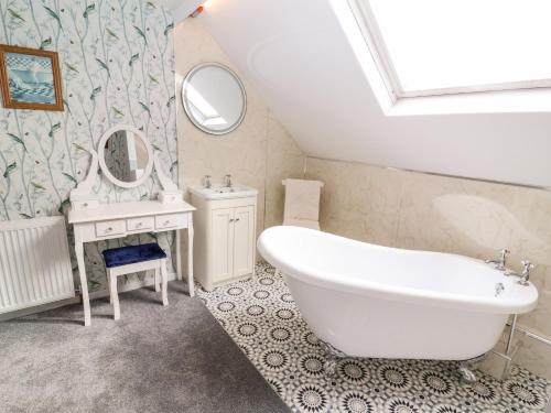 a bathroom with a tub and a sink and a mirror at Through the Looking Glass in Ripon