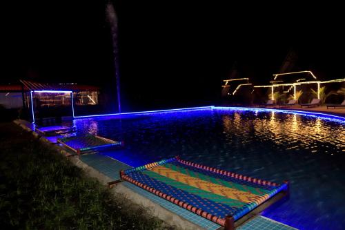 una piscina notturna con luci blu di Rama Hills Unity Resort a Lāchharas