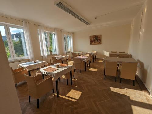 a dining room with tables and chairs and windows at Hotel Gästehaus Altena in Altena