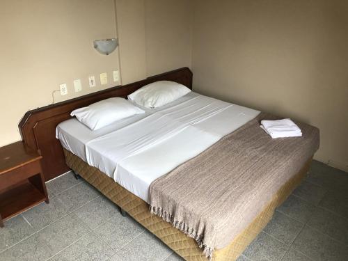 1 dormitorio con 1 cama grande con sábanas blancas en HANNA Praia Hotel - Florianópolis, en Florianópolis