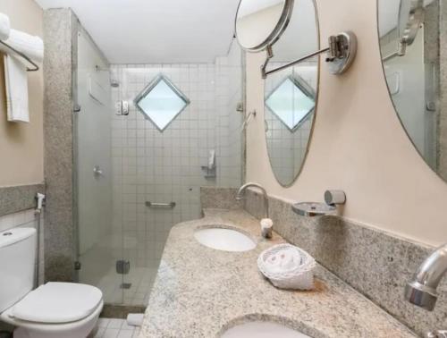 a bathroom with a sink and a toilet and a mirror at Flat Porto de Galinhas in Porto De Galinhas