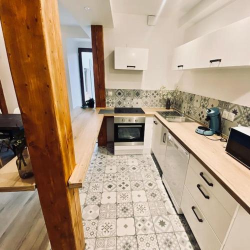 uma cozinha com armários brancos e piso em azulejo em Bel appart proche centre ville, thermes, casino em Bagnères-de-Bigorre