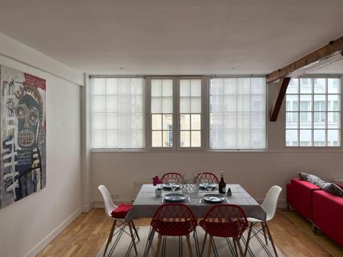 - une salle à manger avec une table, des chaises et un canapé rouge dans l'établissement Loft duplex d'exception de 120m2 Paul Bert, à Paris