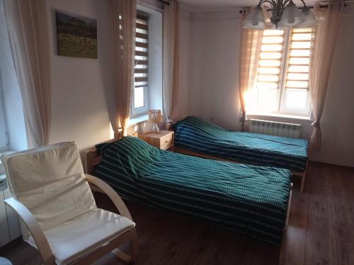 sypialnia z 2 łóżkami i krzesłem oraz 2 oknami w obiekcie Biebrzańskie Zacisze w mieście Goniadz