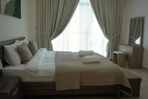 a bedroom with a bed with a large window at Cozy 1BH Apt next to the sea! in Ajman 