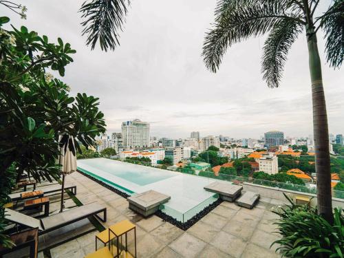 a pool on the roof of a building with palm trees at Serenity Saigon Sky Villas in Ho Chi Minh City