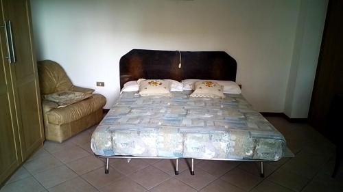 1 cama con cabecero de madera y 1 sofá en una habitación en CASA MAMMA, en Camponogara
