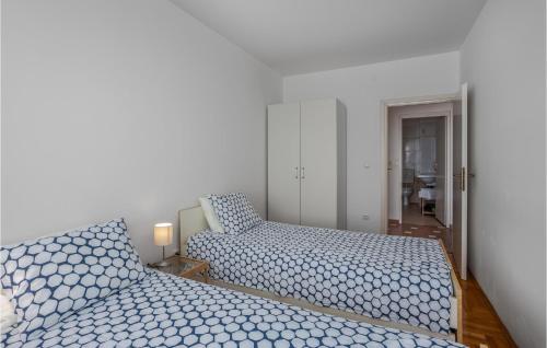 a bedroom with two beds with blue and white sheets at 2 Bedroom Lovely Apartment In Lovran in Lovran