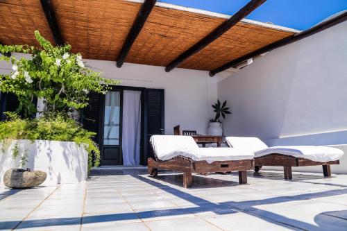 a patio with two beds and a wooden pergola at Quartara Boutique Hotel in Panarea