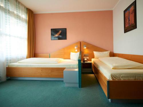 a hotel room with two beds and a window at Sportschule Oberhaching in Oberhaching