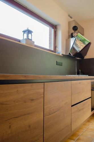 a kitchen with wooden cabinets and a large window at Domaine des Arches in Soumagne
