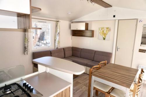 Il dispose d'une cuisine et d'un salon avec un canapé et une table. dans l'établissement Les Pierres Couchées 4 étoiles à St Brévin les Pins emplacement BR22 3CH 2SDB 8 personnes, à Saint-Brévin-les-Pins