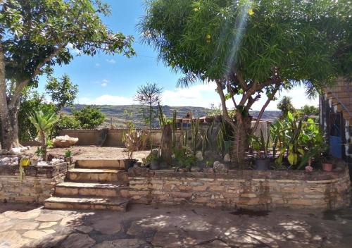a garden with a stone wall and trees and stairs at Diamantina Ecohostel in Diamantina