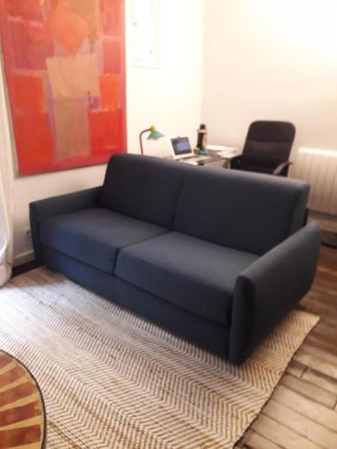 - un canapé bleu dans le salon avec un bureau dans l'établissement Appartement proche Montmartre, à Paris