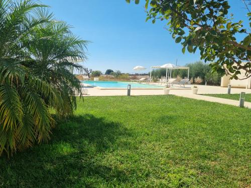 a swimming pool in a yard with a palm tree at Casa Sbrizza in Rosolini