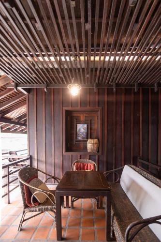 a table and chairs in a room with wooden walls at Ancient Luangprabang Hotel in Luang Prabang