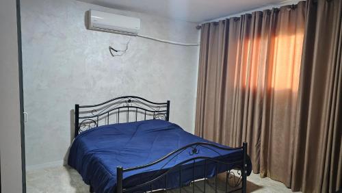 a bedroom with a bed with a blue blanket and a window at merana charlet in Ash Shāghūr