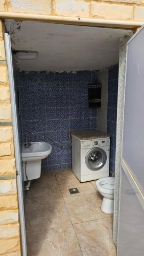 a bathroom with a toilet and a sink and a washing machine at merana charlet in Ash Shāghūr