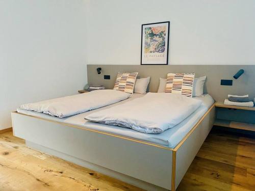uma cama com lençóis brancos e almofadas em Traumhafte Ferienwohnung in historischem Brandmanngut em Marquartstein