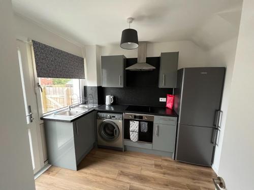 a kitchen with a refrigerator and a washer and dryer at The Wee Hoose Rhu in Rhu