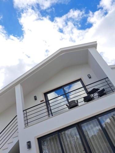 a white house with a balcony with two chairs at Poço e Meio - Padel & Pool in Santiago da Guarda