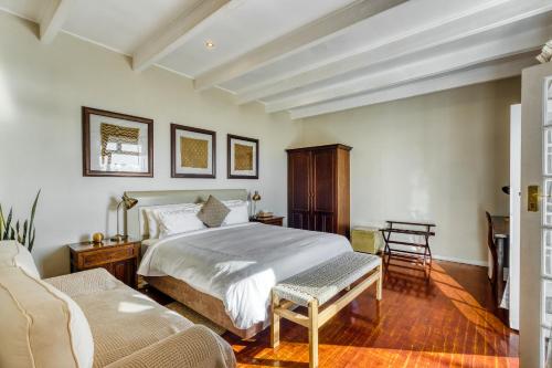 a bedroom with a bed and two chairs in it at Manor on the Bay in Gordonʼs Bay