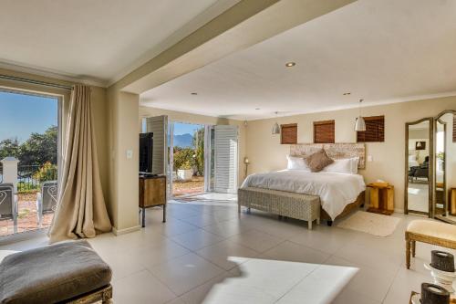 a bedroom with a bed and a large window at Manor on the Bay in Gordonʼs Bay