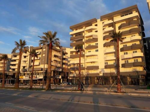 ein Gebäude mit Palmen vor einer Straße in der Unterkunft Apartments Vlora Holidays in Vlorë