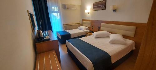 una camera d'albergo con due letti e una televisione di Blue Port Hotel a Burhaniye