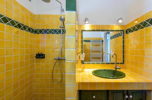 La salle de bains est pourvue de carrelage jaune, d'un lavabo et d'une douche. dans l'établissement le Cadet - vue panoramique ville et baie de SANARY SUR MER, parking & terrasse - 2 à 4 pers, à Sanary-sur-Mer