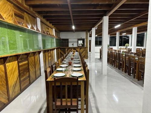 a long dining room with a long table with plates on it at Vila dos pássaros, Quarto 02 in Itapema