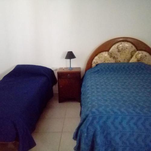 1 dormitorio con 2 camas y mesita de noche con lámpara en los jacarandaes en San Isidro