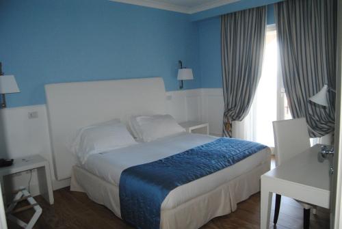 a bed room with a white bedspread and a blue comforter at Helios Hotel in Crotone
