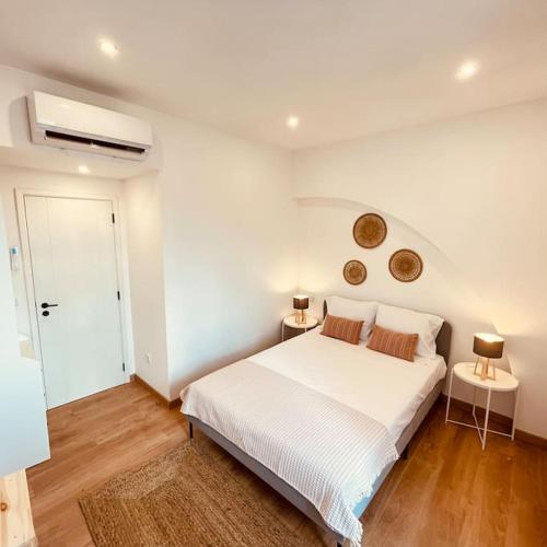 a white bedroom with a white bed and two lamps at Casa Velha Estremoz in Estremoz