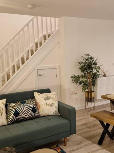a living room with a green couch and stairs at Modern 2bedroom House in Ipswich Suffolk in Ipswich