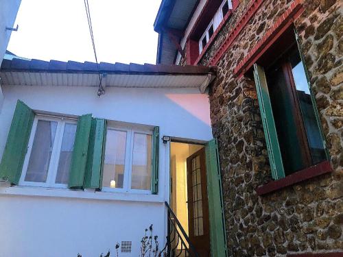ein Gebäude mit grünen Fensterläden und einer Tür in der Unterkunft House Paris 13ème in Ivry-sur-Seine