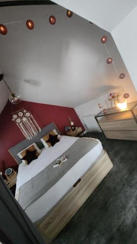 - un grand lit dans une chambre dotée d'un mur rouge dans l'établissement La Parenthèse Étoilée ☆, à Quetteville