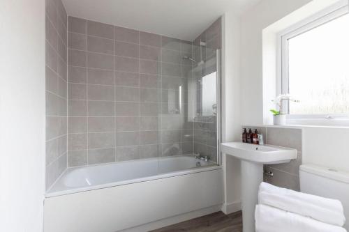 Baño blanco con bañera y lavamanos en Stunning 4 Bed 3 Bathroom Home 