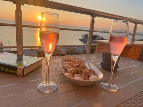 two glasses of wine and a bowl of nuts on a table at Amazing Paradise Sensation 2 Bedroom Luxury Apartment with a Jacuzzi in Durrës