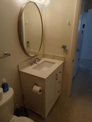 a bathroom with a sink and a mirror and a toilet at Steps from the Gulf of Mexico in Holmes Beach