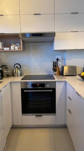 a kitchen with a black oven and white cabinets at Abode Africa in Bloubergstrand