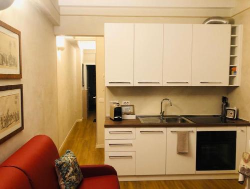 a kitchen with white cabinets and a red couch at COSTHOUSE in Brescia