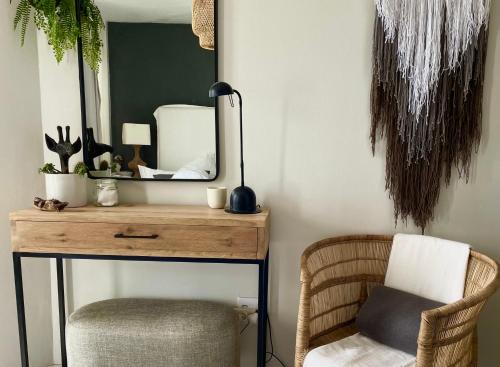 een kaptafel met een spiegel en een stoel bij Abode Africa in Bloubergstrand