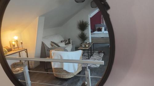 un miroir reflétant une pièce avec un lit et une chaise dans l'établissement La Parenthèse Étoilée ☆, à Quetteville