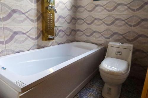 a bathroom with a white tub and a toilet at RESIDENCE LINO LE BENGUISTE in Yaoundé