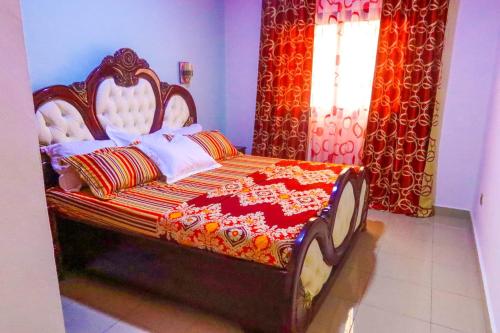 1 dormitorio con 1 cama con edredón rojo y naranja en RESIDENCE LINO LE BENGUISTE, en Yaoundé