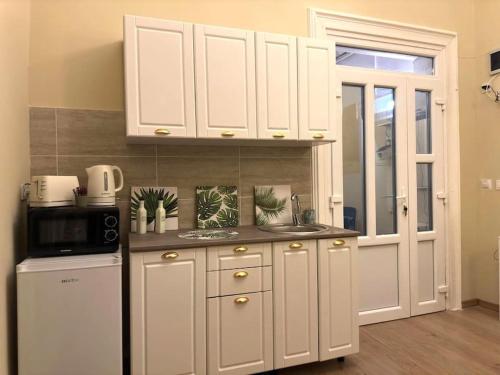 a kitchen with white cabinets and a sink and a refrigerator at Studio Montaldo in Braşov