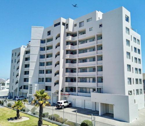 a white apartment building with a van parked in front of it at Abode Africa in Bloubergstrand