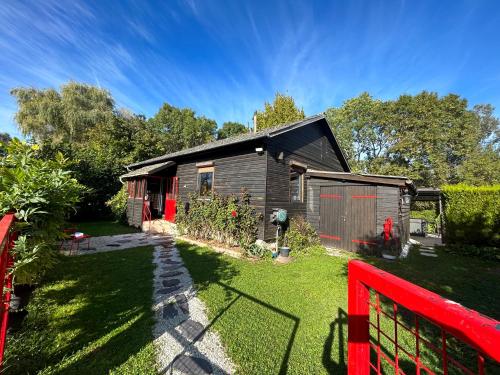ein kleines Haus mit einem roten Zaun im Hof in der Unterkunft Cottage tres bien équipé avec jacuzzi 